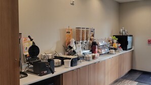 A breakfast bar with coffee machines, a waffle maker, and a juice dispenser. - Microtel Inn & Suites by Wyndham Fountain/Fort Carson (Fountain)