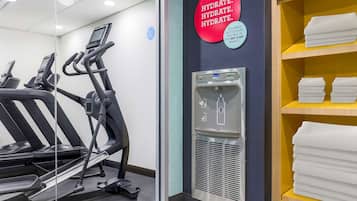 Een fitnessruimte met loopbanden, een waterfontein en een plank met handdoeken.