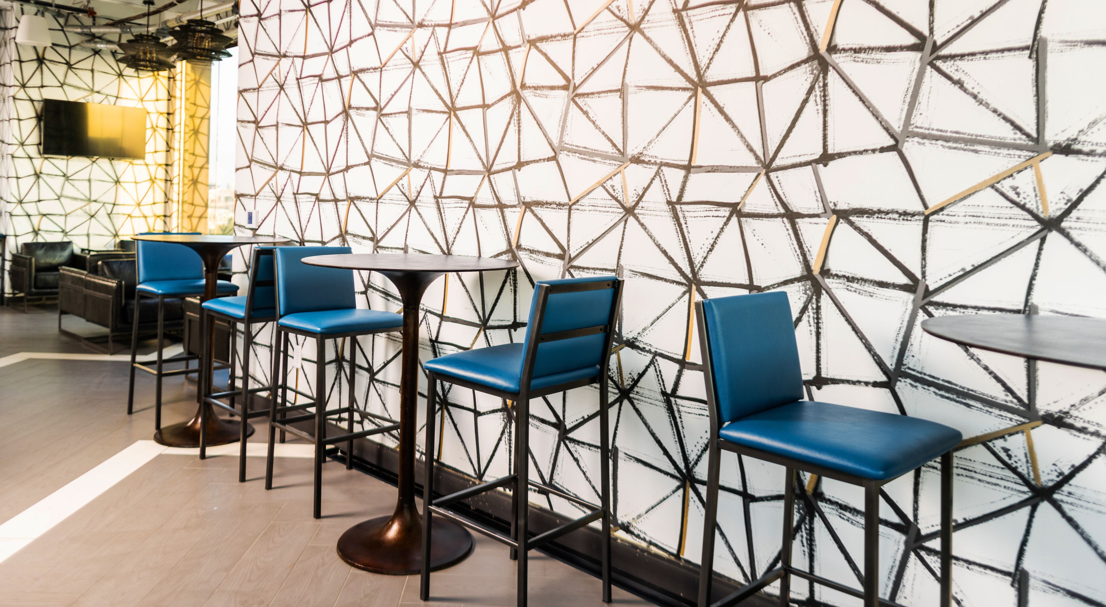 Uma área de bar moderna com banquetas altas e um design geométrico na parede.