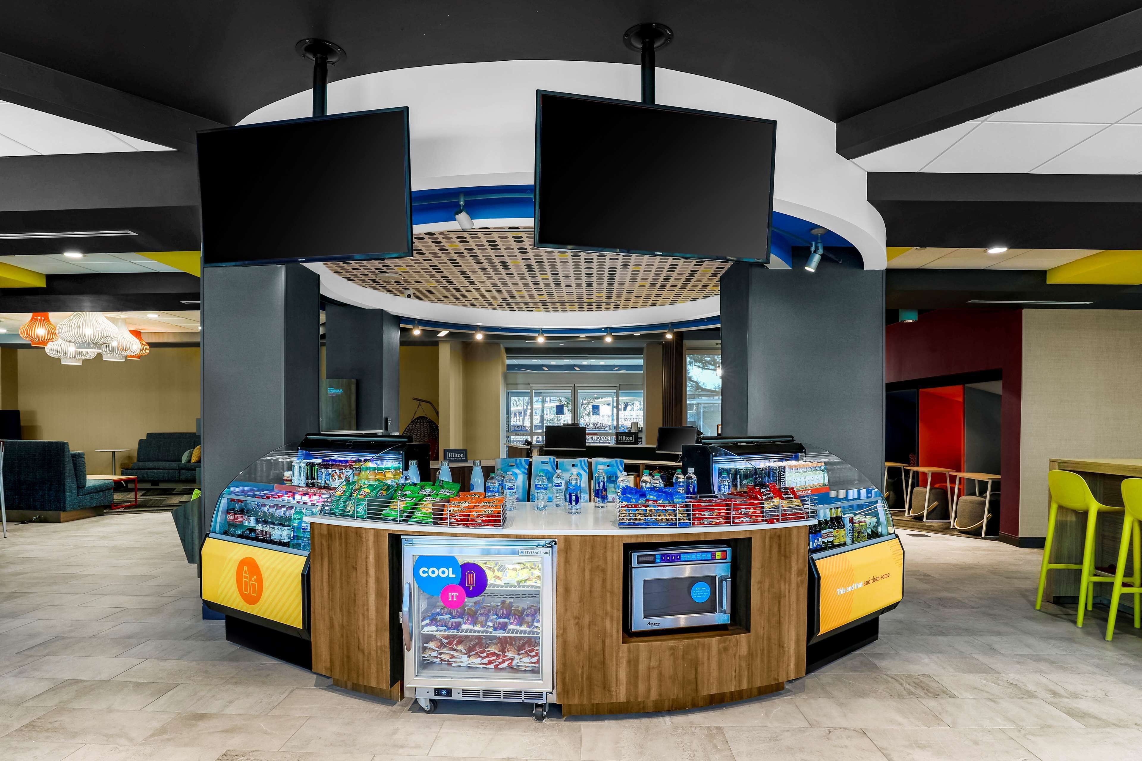 Een toonbank met een drankdispenser, een koelvitrine en een digitaal scherm.