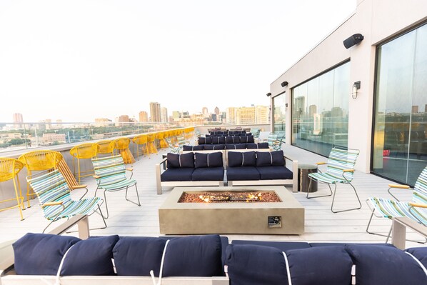A rooftop terrace with outdoor seating, a fire pit, and a city view. - Tru by Hilton Dallas Downtown Market Center (Dallas)