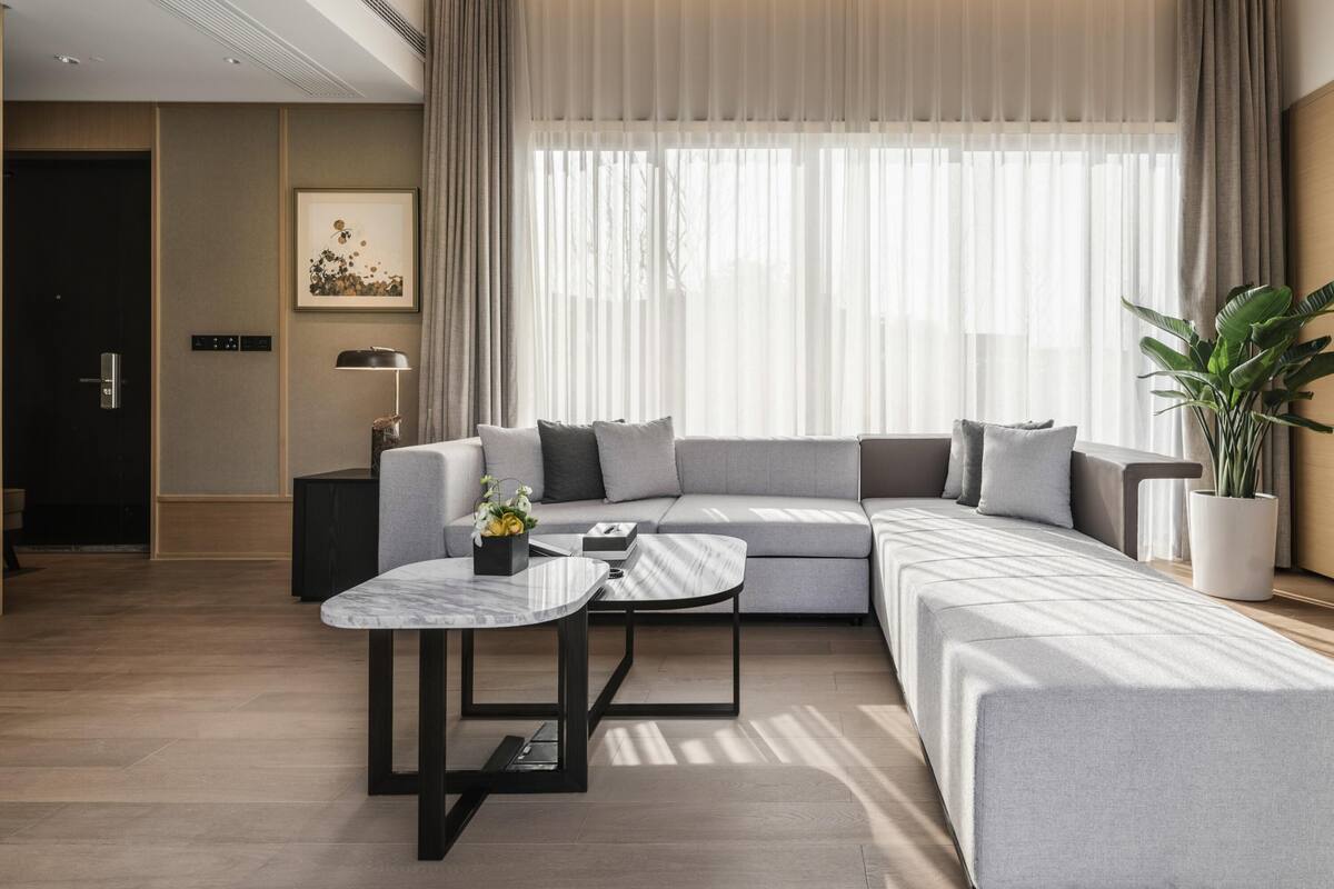 A modern living room with a sectional sofa, a marble coffee table, and a potted plant.