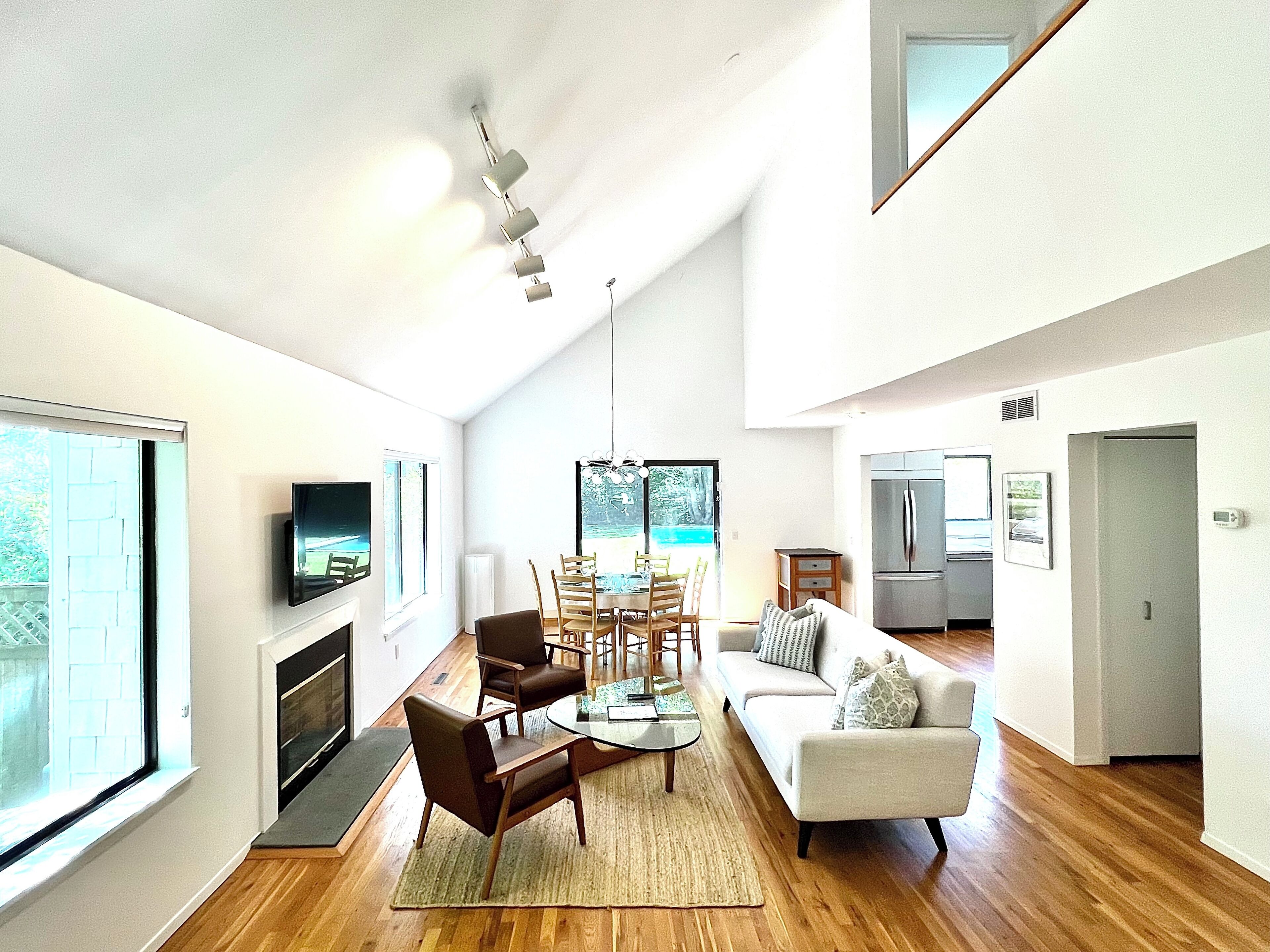 A modern living room with a fireplace, dining area, and kitchen.