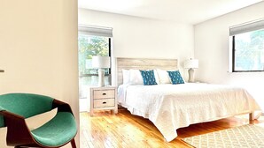A bedroom with a bed, bedside tables, a chair, and a window. - Modern East Hampton Oasis – Heated Pool & Just Steps to Village (East Hampton)