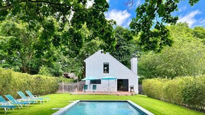A house with a pool, surrounded by a well-maintained lawn and trees. - Modern East Hampton Oasis – Heated Pool & Just Steps to Village (East Hampton)