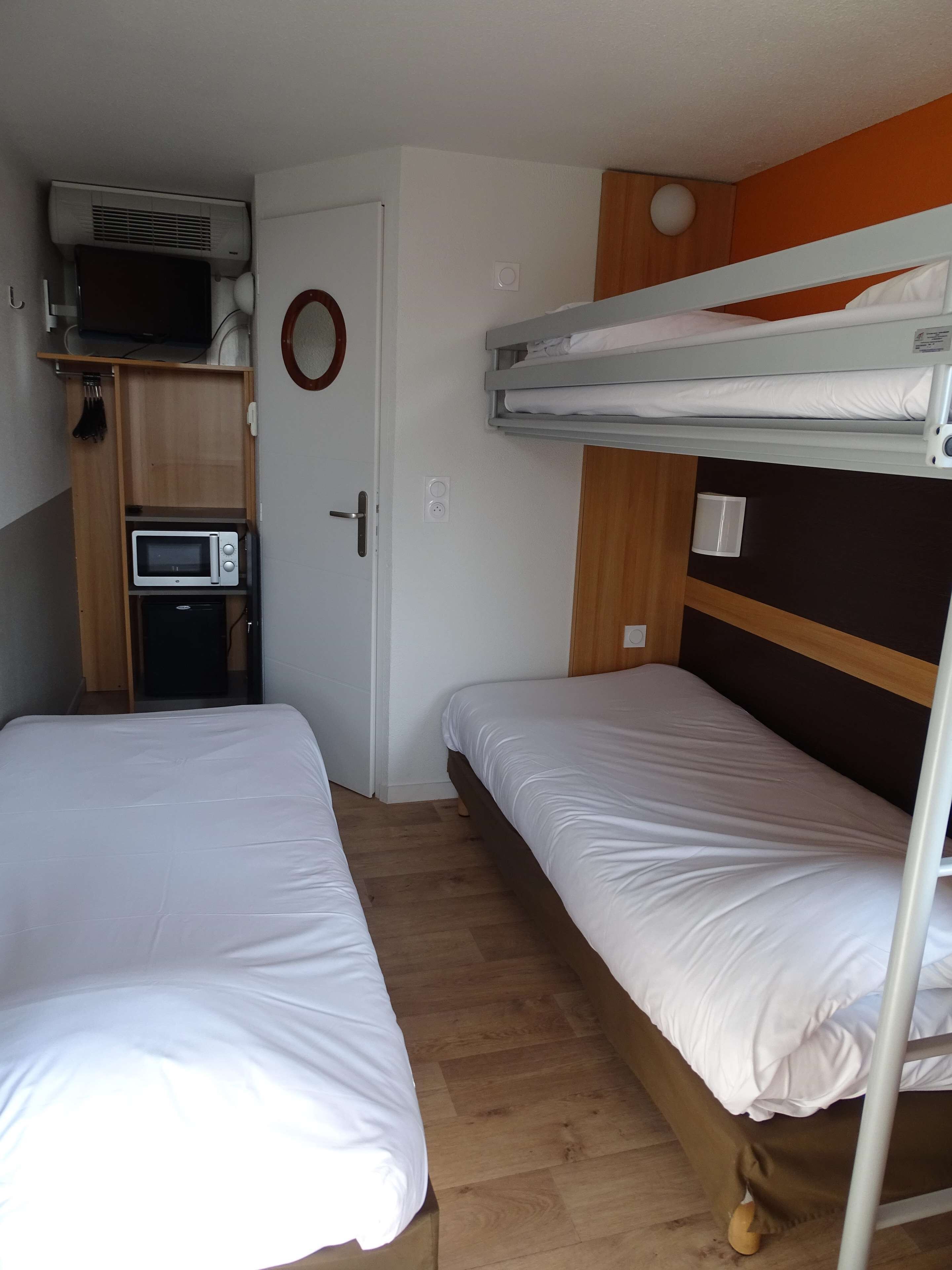 Ein kleines Zimmer mit Etagenbetten, einer Mikrowelle und einer kleinen Küchenzeile.