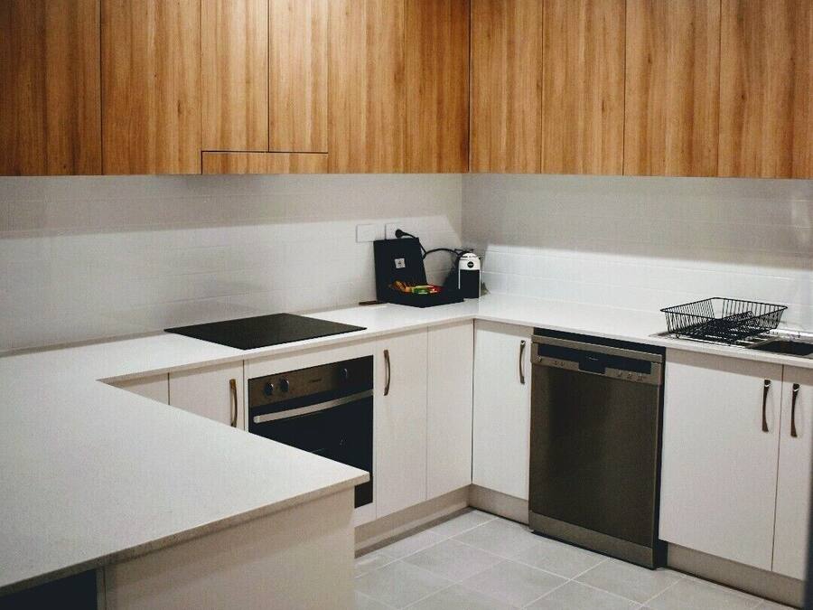 A modern kitchen with white cabinetry, a black stove, and a dishwasher.