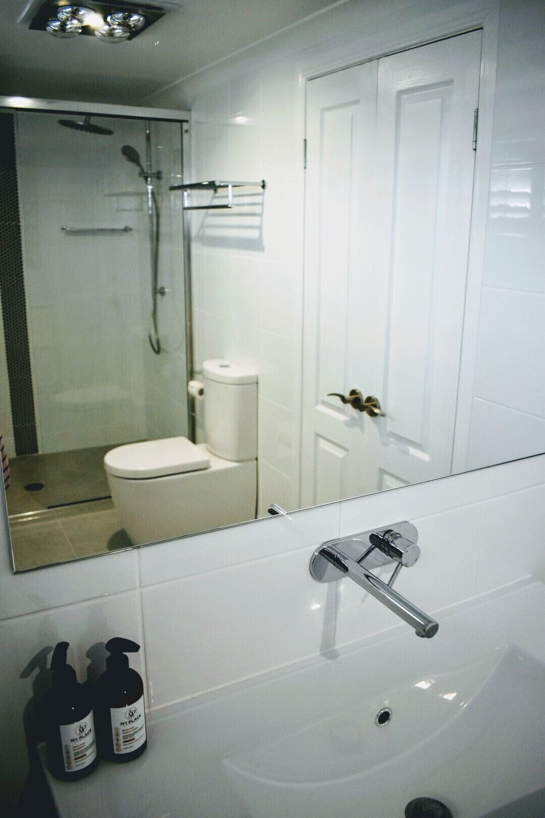 A bathroom with a white sink, a mirror, and a shower.