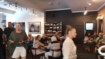 L’intérieur d’un restaurant, avec un bar, des tables et des chaises, et un présentoir à vin.