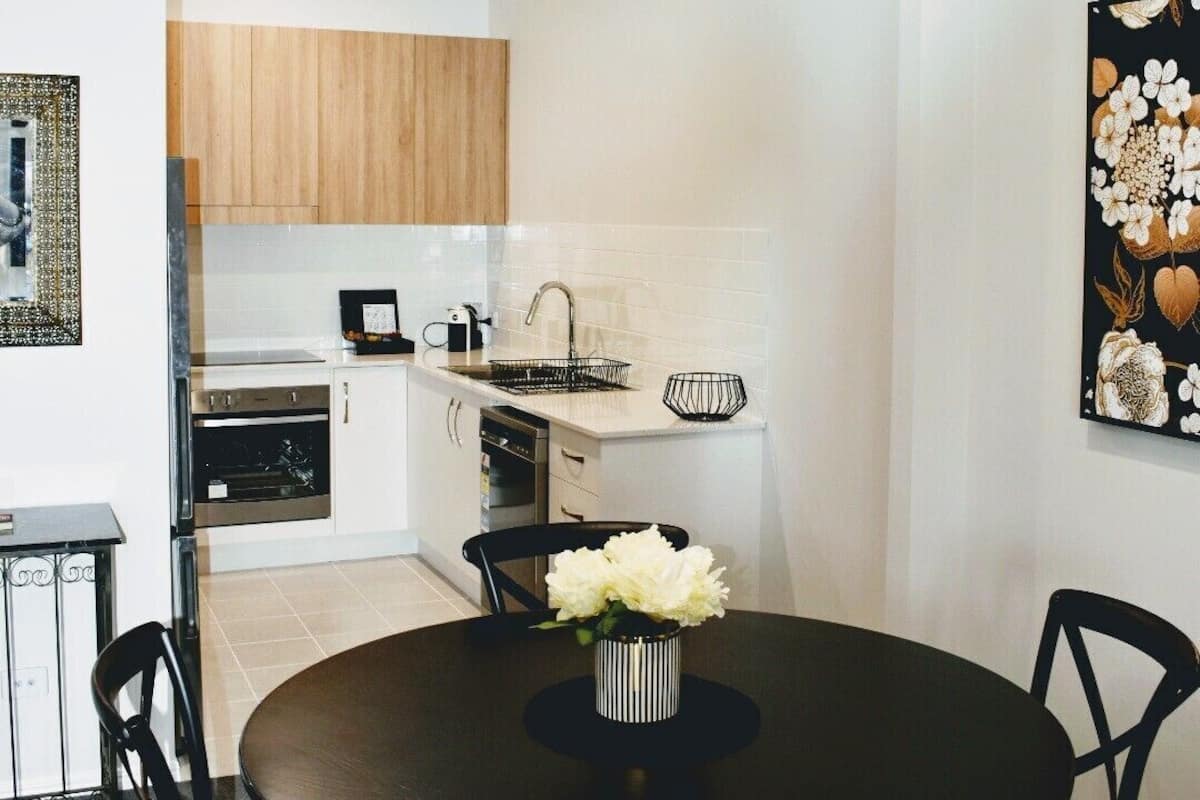 A modern kitchen with white cabinets, a black countertop, and a dining area with a round table and chairs.