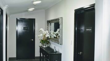 A hallway with black doors, a mirror, and a vase of white flowers on a console table.
