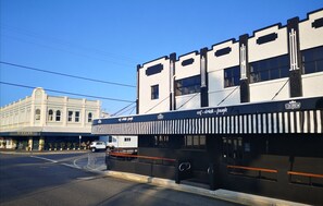 A building with a black and white facade, a sign for 'COCOBREW' with a slogan, and a 'DINGLES' sign on the left. - CocoBrew Boutique Apartments (Rockhampton)