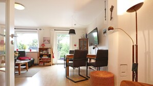 A living room with a dining area, a television, and a bookshelf.