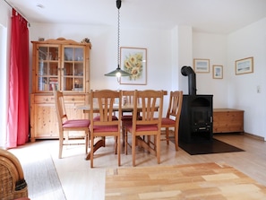 Un coin repas avec une table et des chaises en bois, un buffet, une suspension et une cheminée.