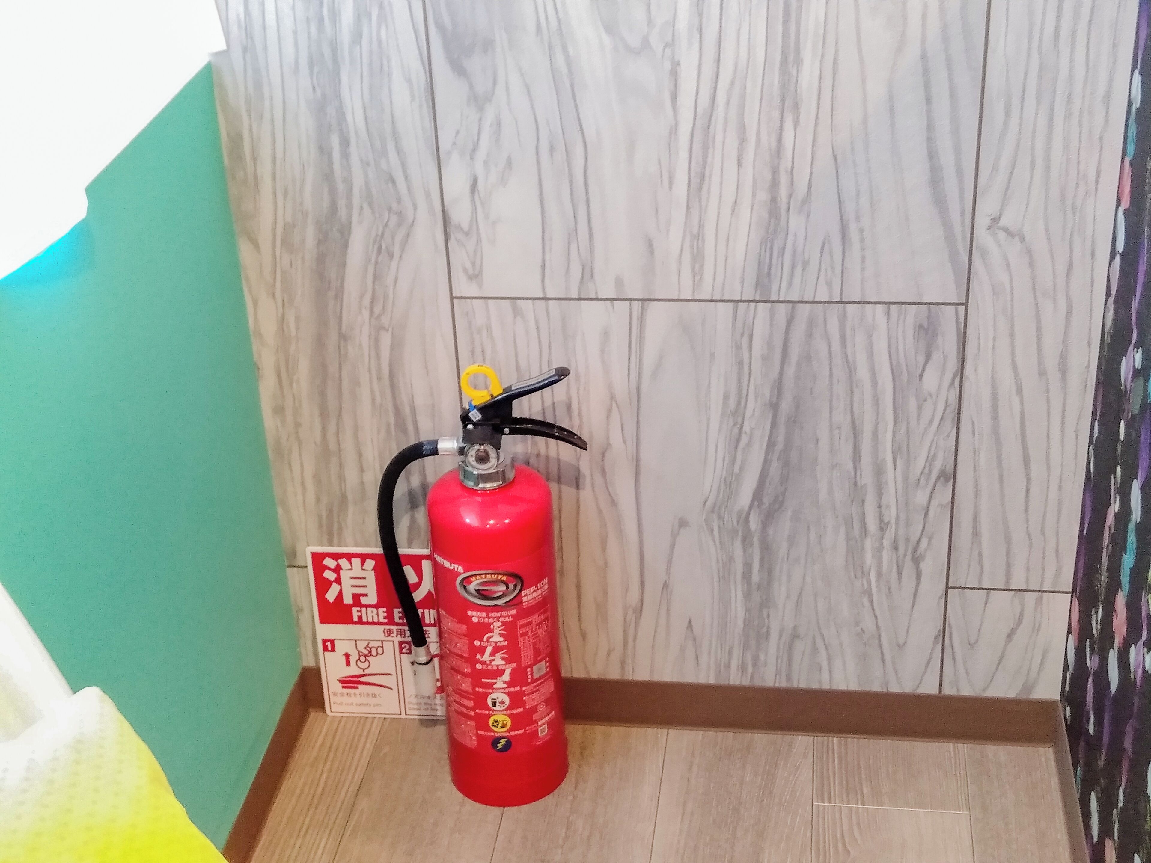 A red fire extinguisher mounted on a wall with a fire safety sign beside it.