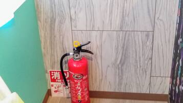 A red fire extinguisher mounted on a wall with a fire safety sign beside it.