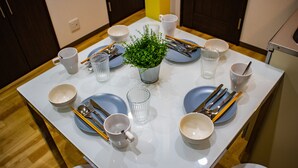 A dining table set with plates, bowls, cups, and cutlery, centered with a potted plant. - Sakura Villa Osaka (Osaka)