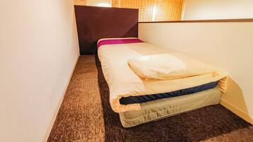 A small, cozy room with a single bed, a wooden ceiling, and a carpeted floor.