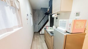 A compact kitchen with a microwave, refrigerator, and a small countertop. - Sakura Villa Osaka (Osaka)