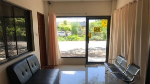 A waiting area with a black sofa and metal chairs, a glass door with a 'closed' sign, and a view of the street outside.
