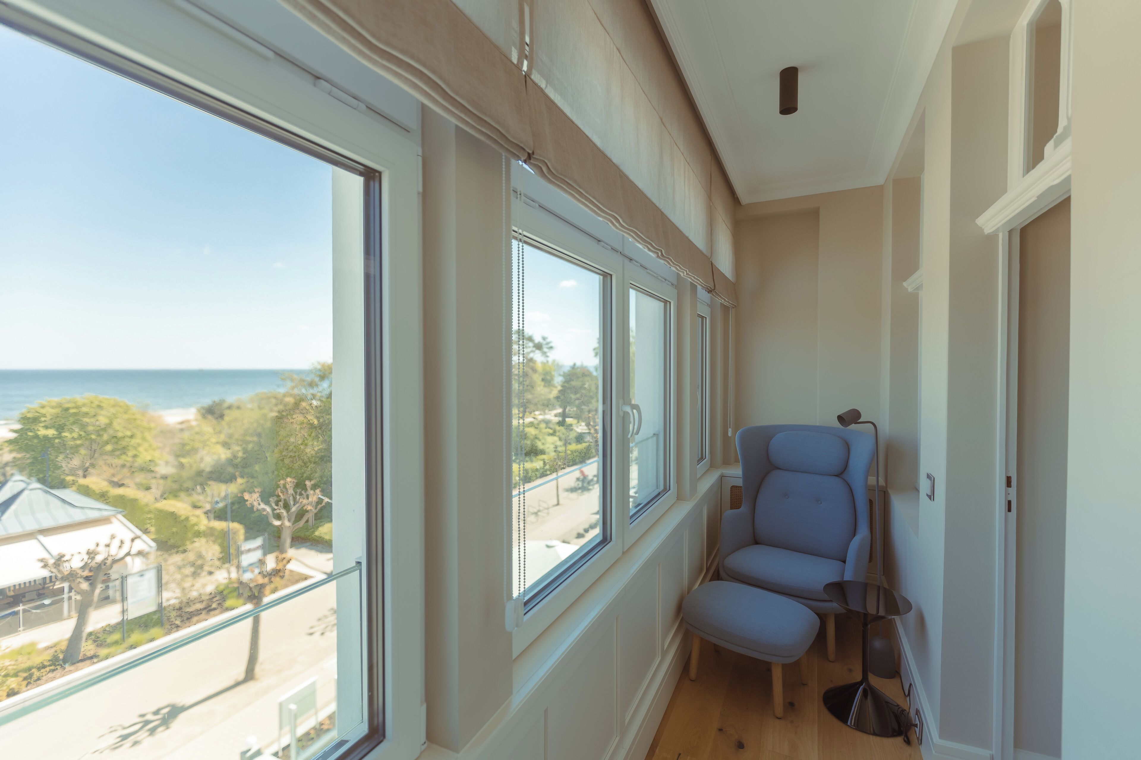 A room with large windows, a blue chair, and a small table.