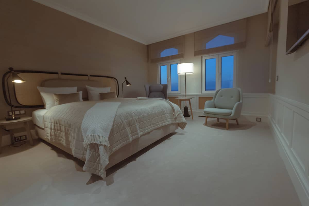 Ein Hotelzimmer mit einem großen Bett, zwei Stühlen, einem Nachttisch und einem Fenster mit Blick.