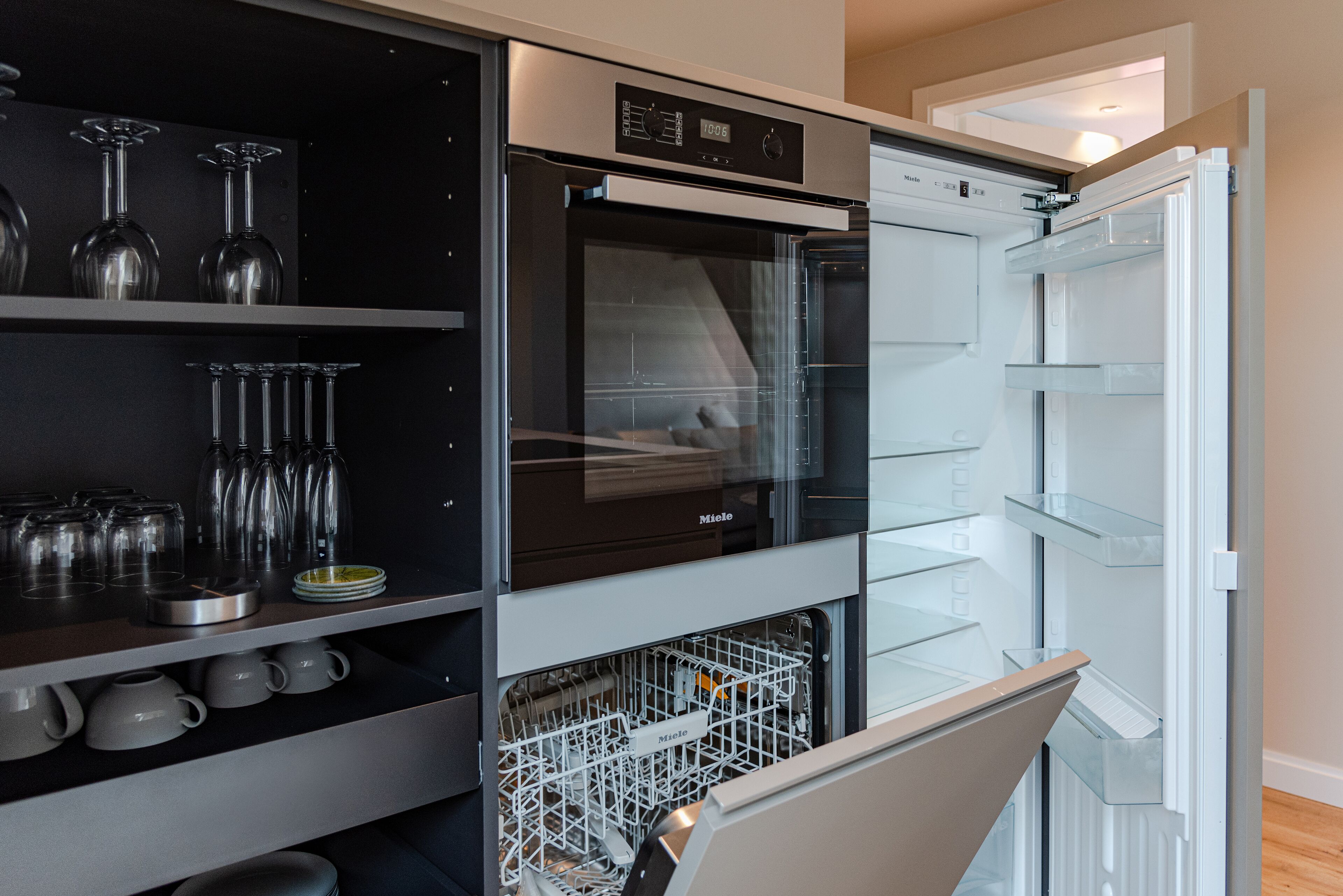 Una cocina moderna con horno empotrado, lavavajillas y espacio para vinos.
