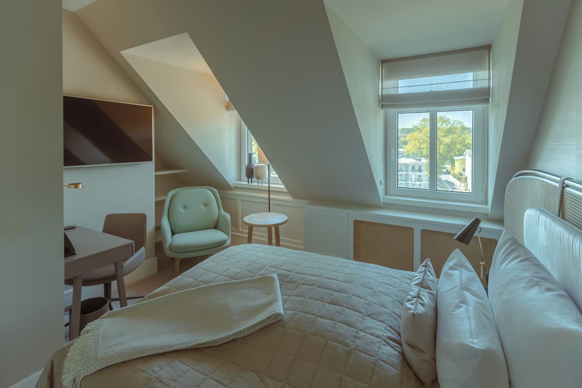 Ein Schlafzimmer mit Bett, Schreibtisch, Stuhl und Fenster.