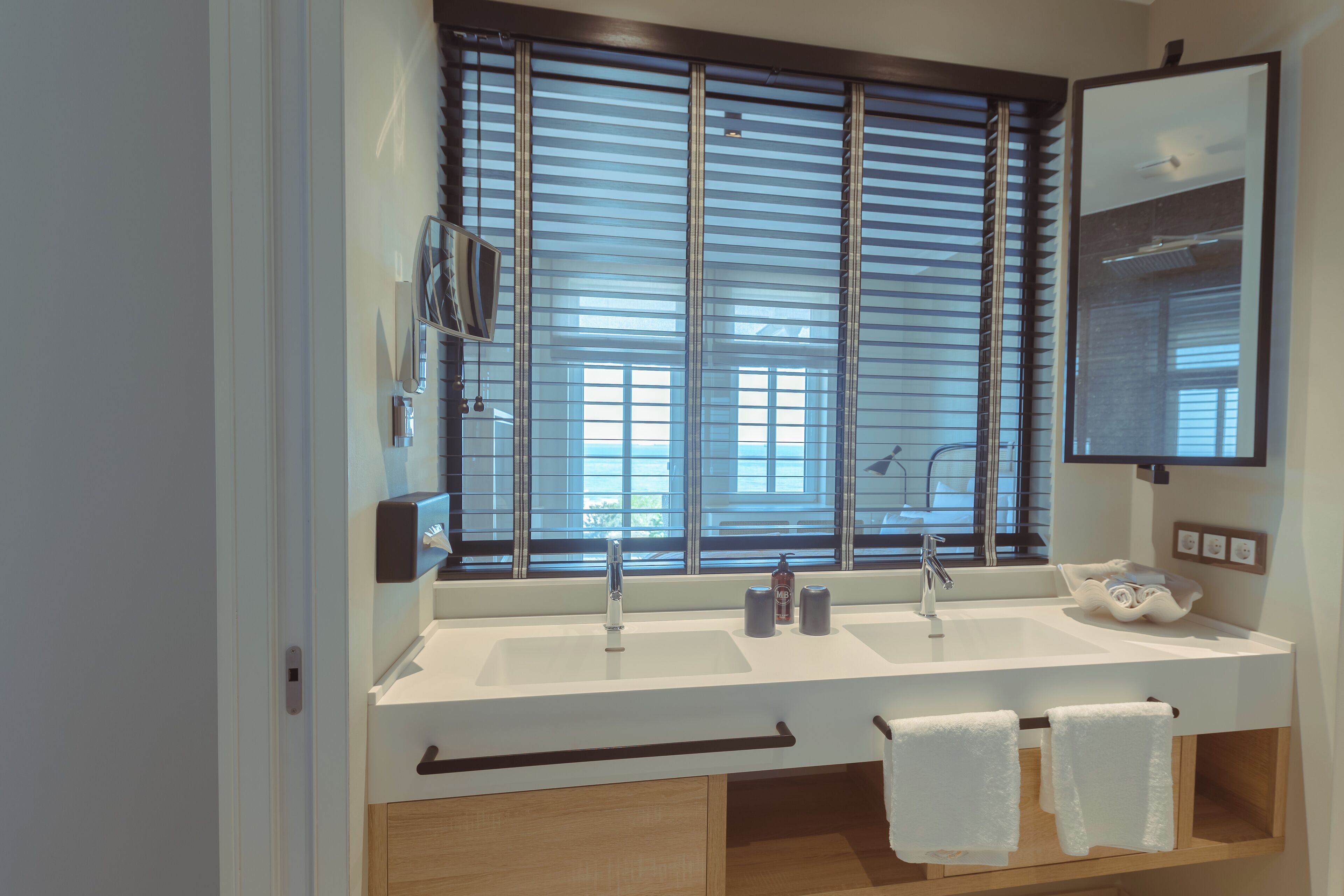 Ein modernes Badezimmer mit großem Fenster, zwei Waschbecken und einem Spiegel.