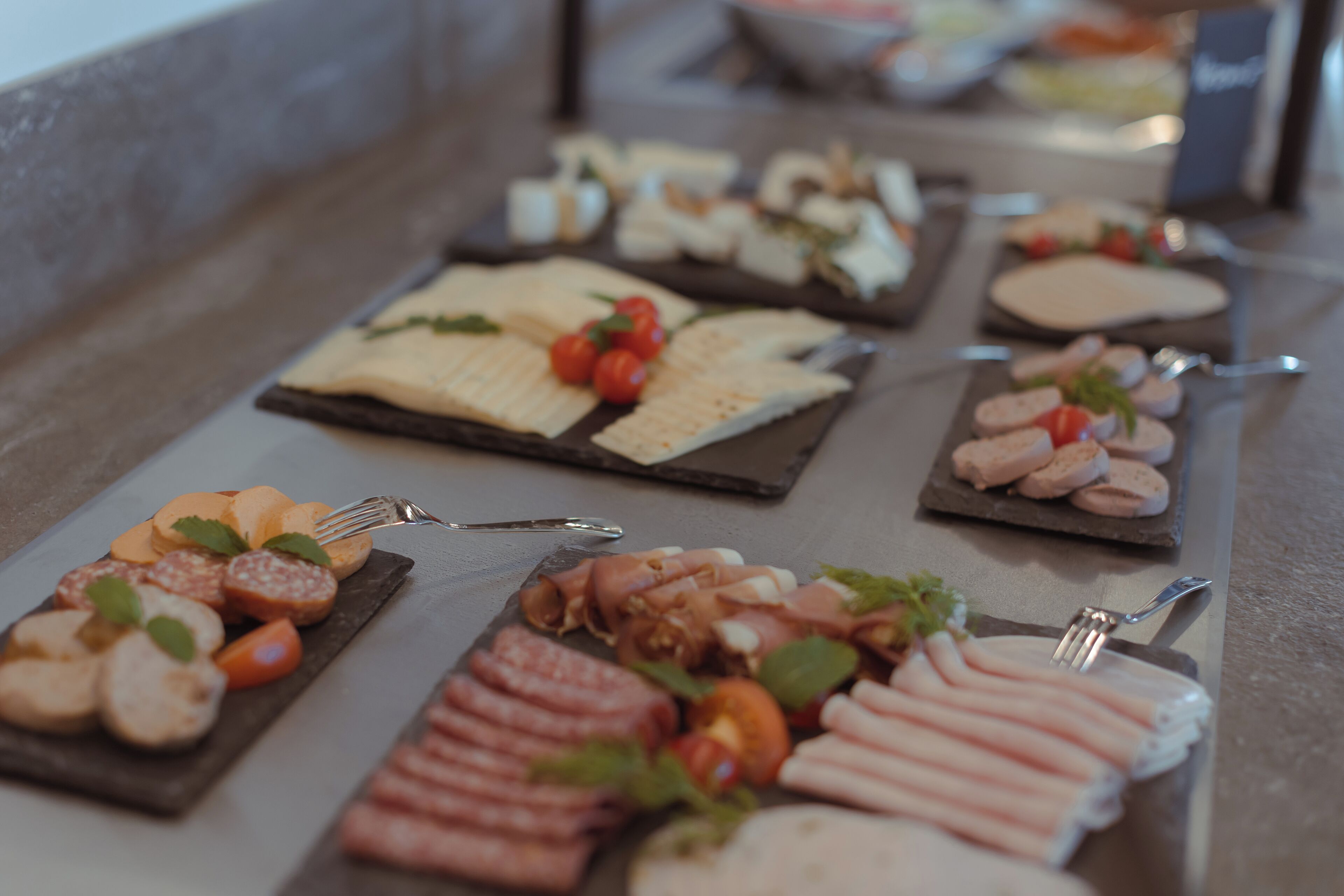 A buffet with various food items including meats, cheeses, and vegetables.
