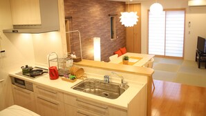 A modern kitchen with a built-in oven, a sink, and a dining area with a table and chairs. - GuestHouse SagaArashiyama (Kyoto)