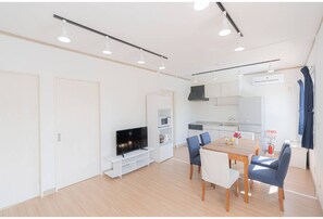 Compact living space with a flat-screen TV, kitchenette, and dining area.