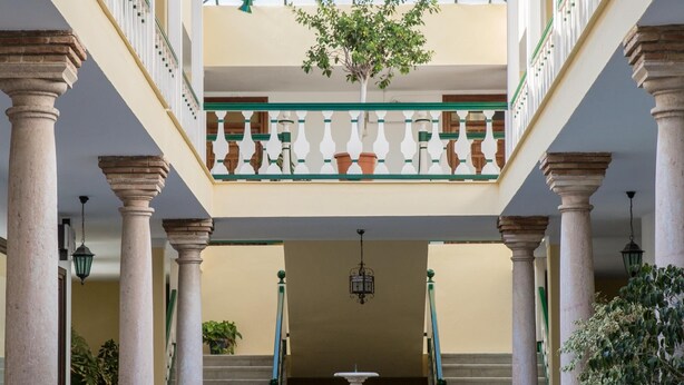 Un patio con columnas, una fuente y plantas en macetas.