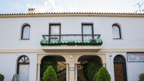 Un edificio con un balcón, dos plantas en macetas y un letrero.
