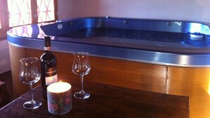 Une table en bois, un jacuzzi, deux verres à vin et une bougie.
