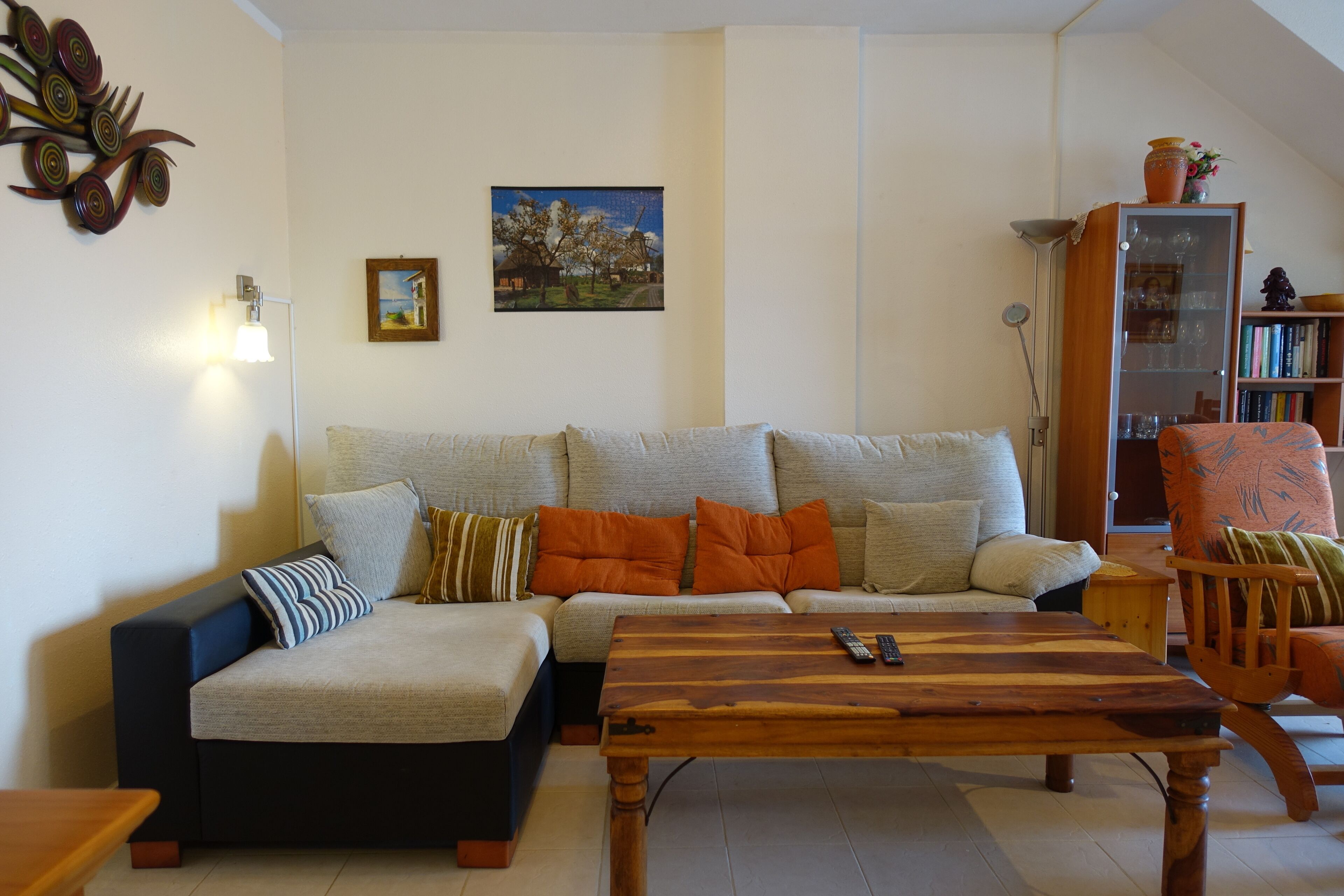 Una sala de estar con un sofá modular, una mesa de centro de madera y una estantería.