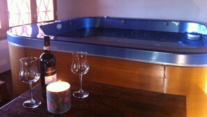 Een houten tafel met een jacuzzi, twee wijnglazen en een kaars.