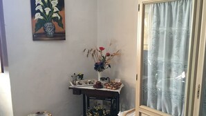 Een kamer met een gedekte tafel voor thee, een vaas met bloemen, een mand en een kast met een gordijn.
