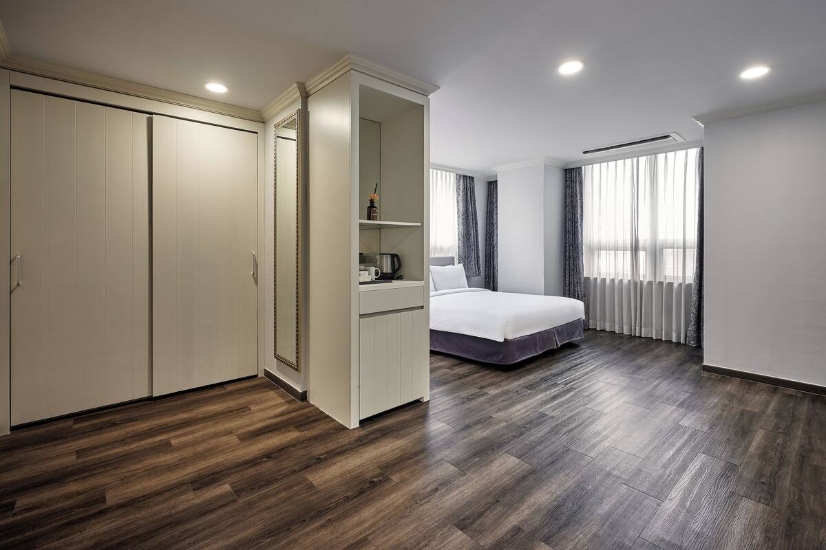 Un dormitorio moderno con una cama grande, un armario y una estantería empotrada con una tetera.