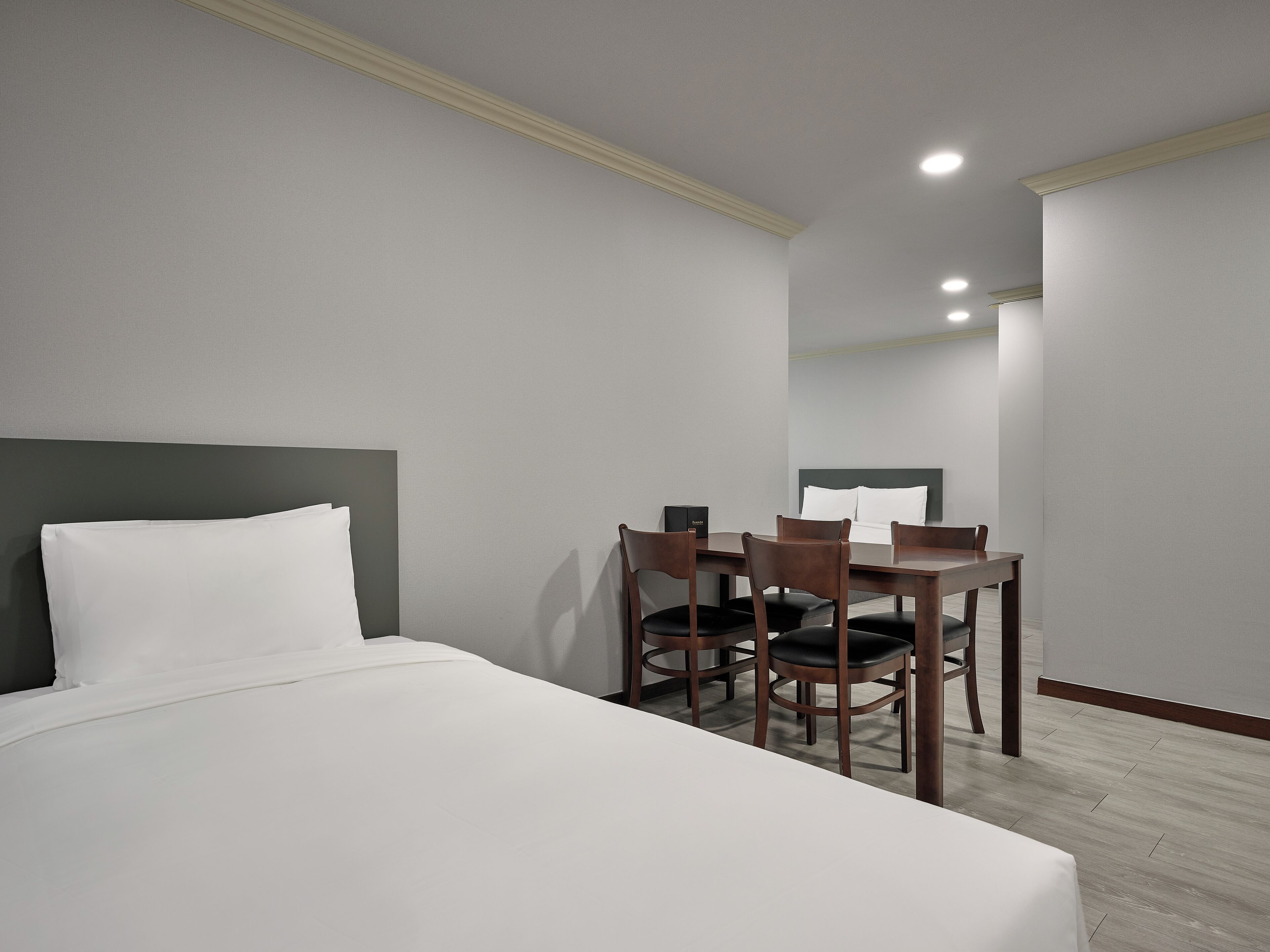 A hotel room with a bed, a desk with chairs, and a headboard.
