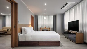 A modern hotel room with a large bed, a TV, a wooden side table, and a sofa in the background. - Ramada Hotels & Suites Seoul Namdaemun (Seoul)