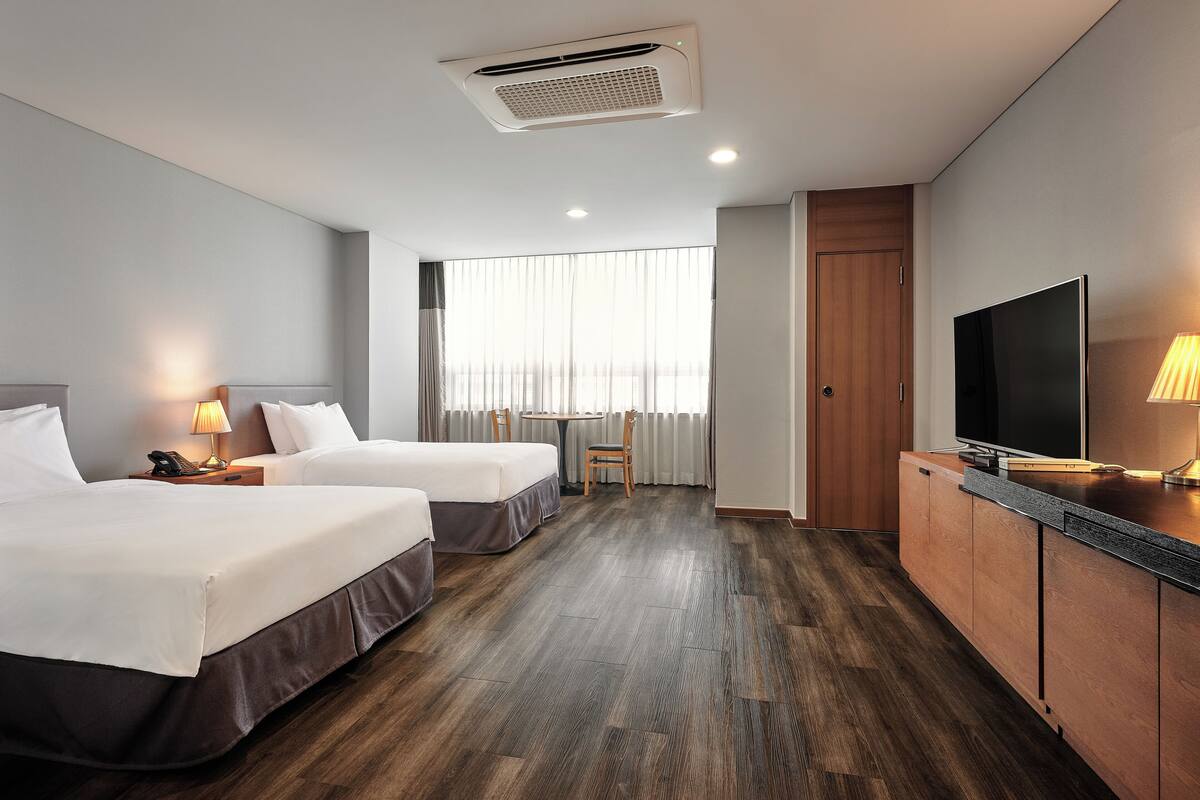 Habitación de hotel con dos camas, televisión, escritorio y una silla.