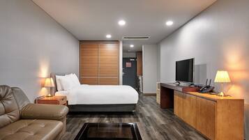 Una habitación de hotel con cama, escritorio, televisor y sofá.