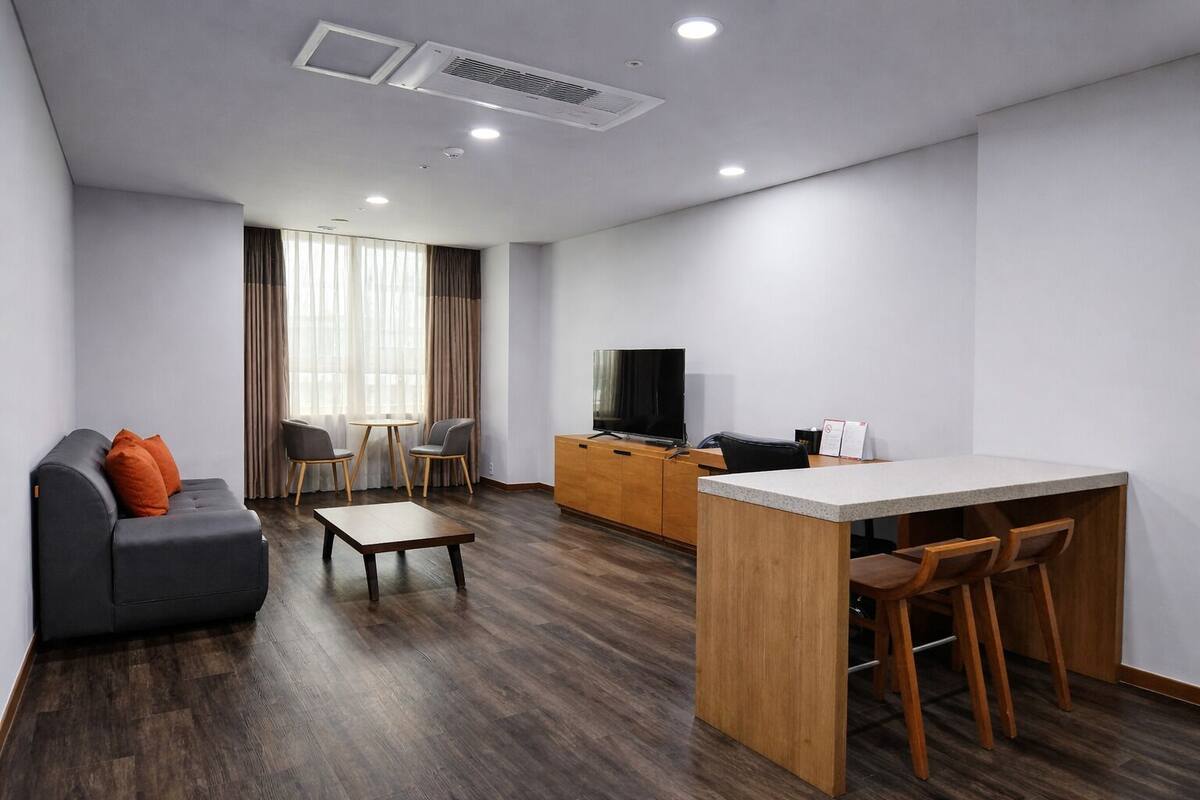 Una sala moderna con un sofá, una mesa de centro, un televisor y un comedor con sillas.