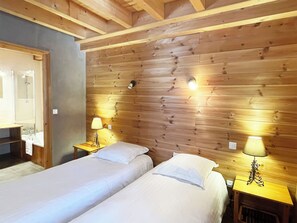 A hotel room with two beds, wooden paneling on the walls, and two bedside lamps.