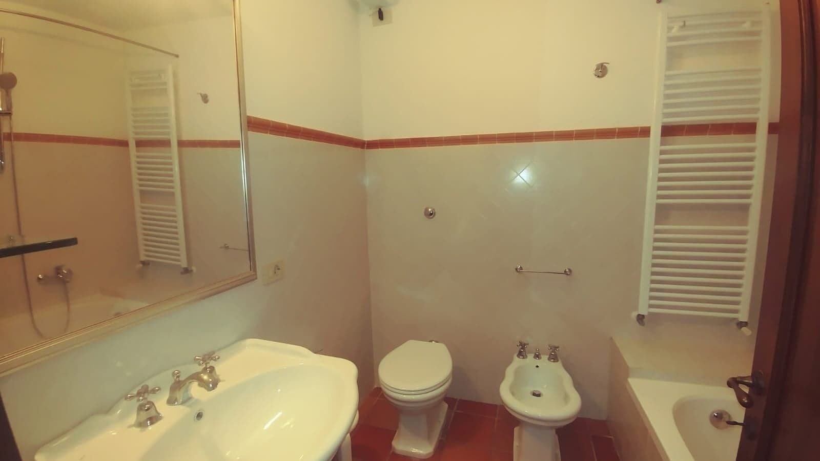 Une salle de bain équipée d’un lavabo, de toilettes, d’un bidet et d’un miroir.