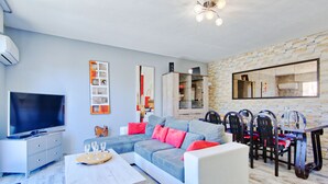 Una sala de estar moderna con un sofá modular, una mesa de comedor, sillas y un televisor de pantalla plana.