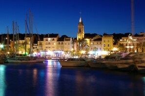A marina with boats docked, a prominent church tower, and buildings with balconies.