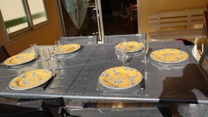A dining table set with yellow plates and clear glasses, with a window and a door in the background. - PORTISSOL T2 TERRACES SEA VIEW 100M BEACH (Sanary-sur-Mer)