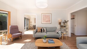 A modern living room with a grey sofa, a purple armchair, and a wooden coffee table.